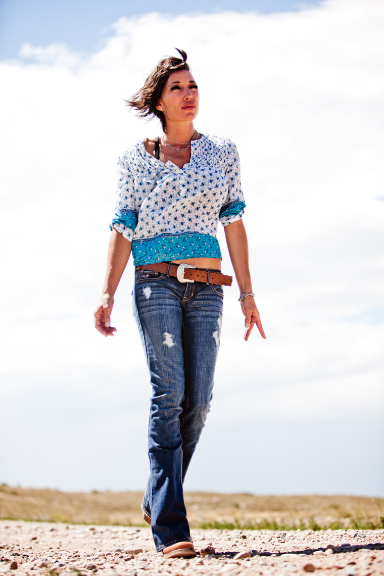 A portrait and of an attractive, beautiful, glamourous, sexy, fun, woman, showcasing her beauty, femininity as she walks a gravel road. She wears distressed jeans and a flowy blouse. This portrait was created by Steve Glass, owner of Glass Photography Portrait Studio. Steve offers a beauty portrait service (a makeover portrait) session, where professional hair, professional makeup, professional styling, are provided in the sitting fee. In all of his portraits they are looking to uncover the unique interests, creativity and beauty that each person possesses. This deepest portion of a person that is created in the image of God, the Imago Dei. Steve Glass, a professional portrait photographer of Glass Photography services the men, women, children, kids, families, business and people of Fort Collins, Windsor, Loveland, Wellington and the surrounding areas of Northern Colorado and southern Wyoming (and sometime Denver), through professional photography by creating timeless portraits and heirloom prints, ranging from corporate portraits, corporate headshots, environmental portraits, editorial portraits, and beauty portraits. 