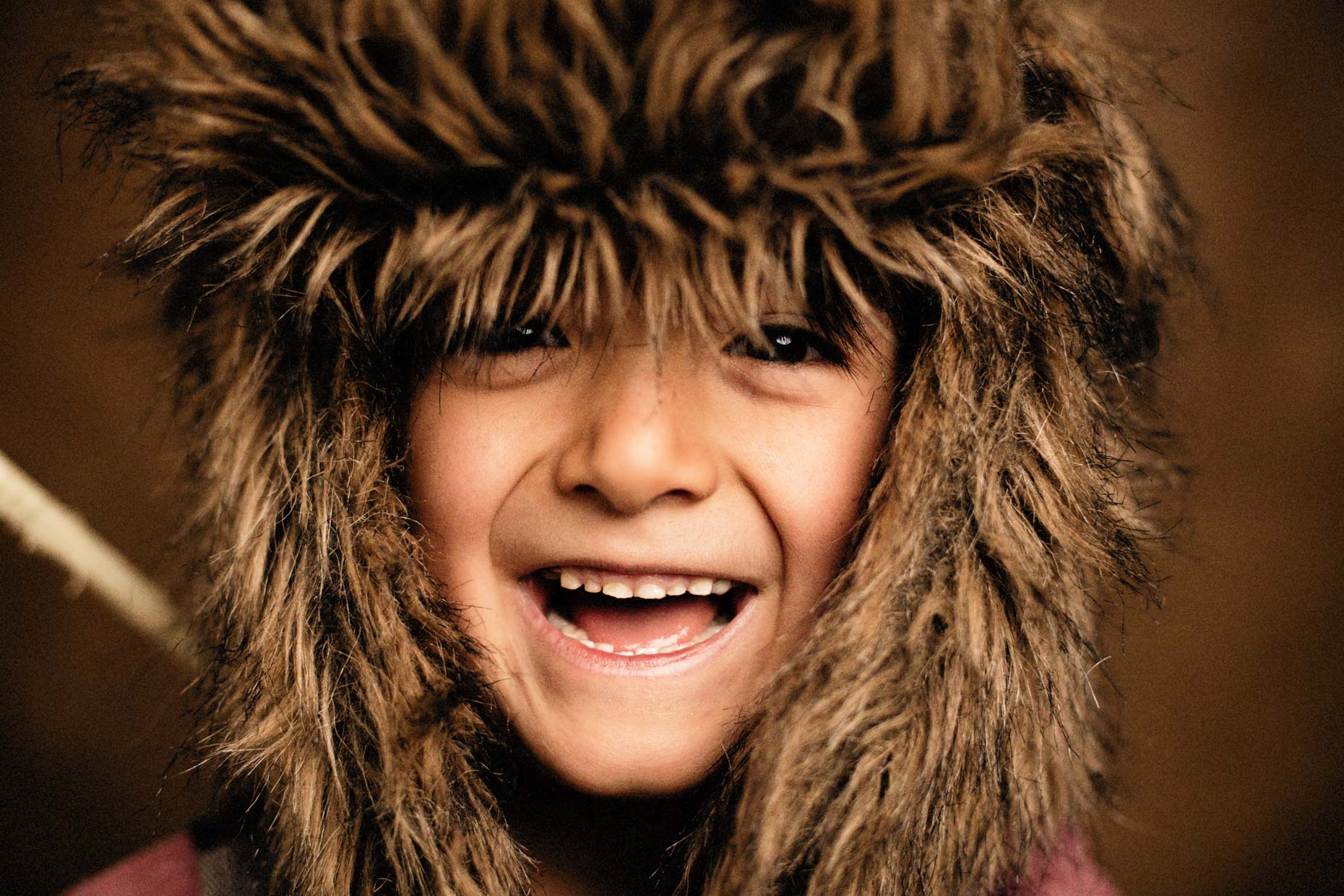 A studio portrait of a strong, handsome 7-year-old boy who is a mountain man at hat. Here he wears his mountain man vest, a pelt hat, and has a bow and arrow that he made. Someday he wants to build a cabin and live in the middle of the woods. This portrait was created by Steve Glass, owner of Glass Photography Portrait Studio. In all, of his portraits he is seeking the Imago Dei – the image of God – in each of his subjects. This means uncovering the unique interests, creativity, ingenuity and beauty that each person possesses. This deepest portion of a person that is created in the image of God, the Imago Dei. Steve Glass, a professional portrait photographer of Glass Photography services the men, women, children, kids, families, business and people of Fort Collins, Windsor, Loveland, Wellington and the surrounding areas of Northern Colorado and southern Wyoming (and sometime Denver), through professional photography by creating timeless portraits and heirloom prints, ranging from corporate portraits, corporate headshots, environmental portraits, editorial portraits, and beauty portraits.