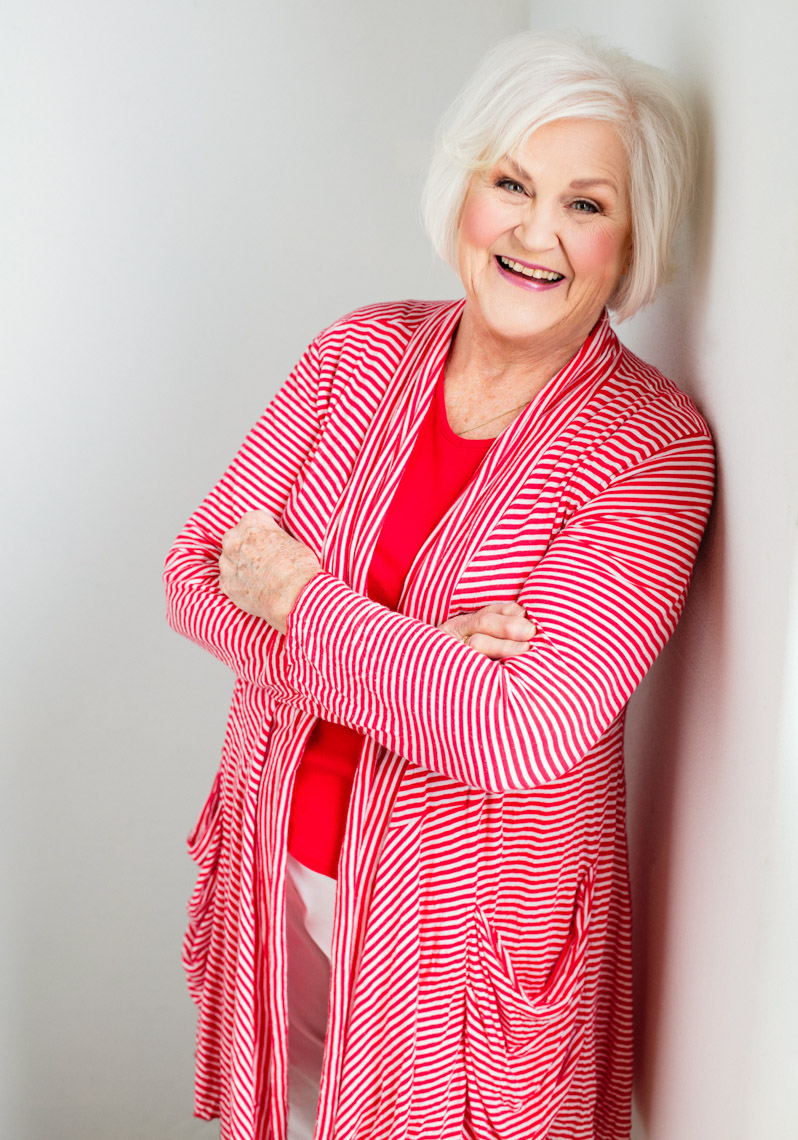 A beauty portrait of Kathryn Glass Addleman, a 75 year old, beautiful woman. This portrait was created by portrait photographer Steve Glass in his portrait studio Glass Photography through their beauty portrait service (a makeover portrait) session, where professional hair, professional makeup, professional styling are provided in the sitting fee. Kathy is red and white striped lightweight cotton cardigan wearing a purple skirt and purple blouse. The portrait reveals her beauty, her femininity, her soul, her fun spirit, her beauty, her fabulous personality. Steve Glass, is a professional portrait photographer of Glass Photography where he services the men, women, children, kids, families, business and people of Fort Collins, Windsor, Loveland, Wellington and the surrounding areas of Northern Colorado and southern Wyoming (and sometime Denver), through professional photography by creating timeless portraits and heirloom prints, ranging from corporate portraits, corporate headshots, environmental portraits, editorial portraits, and beauty portraits.